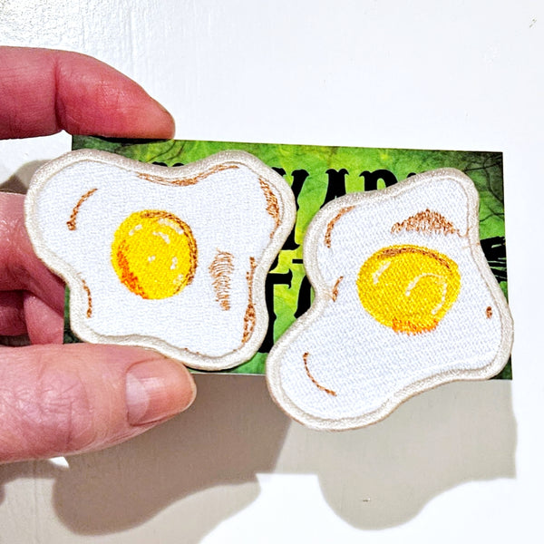 Set of two embroidered twill patches of fried eggs with golden yolks and brown shading