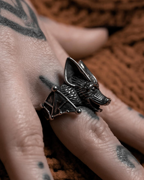 Model wearing a stainless steel ring in the shape of a highly detailed bat’s head and wings. Shown from a left side angle