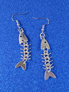 A pair of shiny silver metal dangle earrings with stylized charms in the shape of fishbones