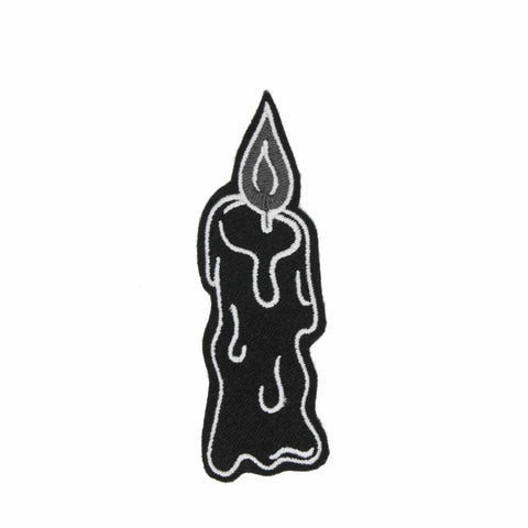 An embroidered patch of a lit melting black candle with white and grey details. Shown flat