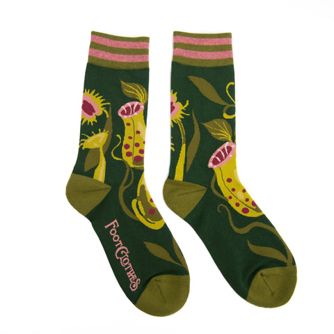 Unisex crew socks with an all-over pattern of pink and green pitcher plants on a dark green background with striped pink and green cuffs, green toes and heels. Shown flat