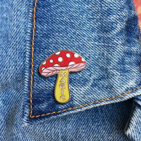 "magic" text on stem red white yellow amanita muscaria mushroom enameled gold metal clutch back pin, shown on a denim jacket