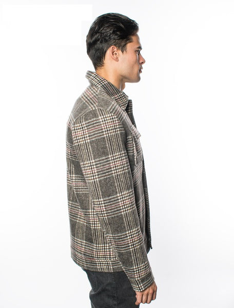 Guy's sizing brown, black, and cream plaid thick flannel jacket with black snaps closure, featuring chest and hand pockets. Shown side view on model.