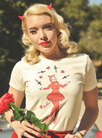 Model wearing a fitted off white t shirt with a print of a pinup-style devil girl juggling black daggers and red hearts