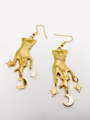 Pair of shiny gold metal left hand with dainty crescent moon and starburst charms dangle earrings
