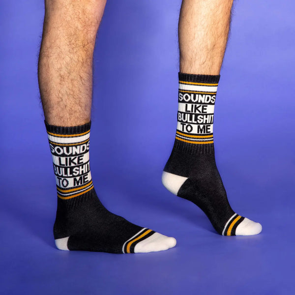 "Sounds Like Bullshit To Me" text and striped design in peach, mustard yellow, and black ribbed knit stretch cotton blend crew length gym socks, seen on a model 