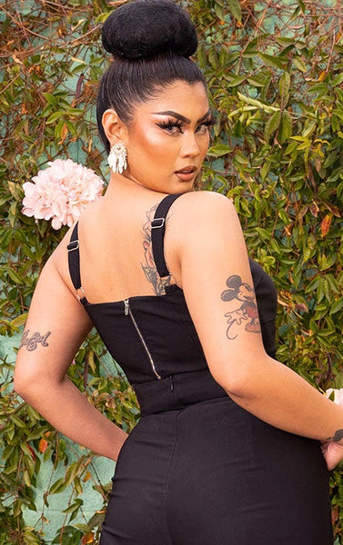 A model wearing a black Bengaline bustier style crop top with a sweetheart neckline and pleating at the bust. Shown from the back to display the silver metal back zipper hardware