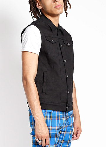 A black denim vest with double chest pockets and hand pockets. Shown on a model from a three quarter angle