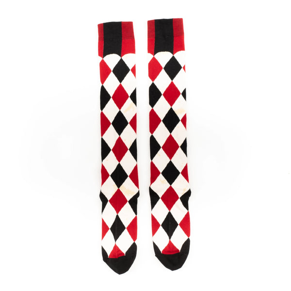 knee socks in a black, red, and cream colored harlequin pattern- with faux-antiqued yellowed age spots throughout each cream colored diamond in the pattern. Shown flat from the front