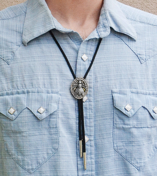 Bolo tie with black cord and silver metal tips with a pendant of a fly on an ornate round plaque. Shown worn by model wearing button up western style shirt