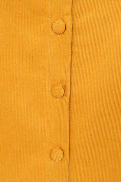 mustard corduroy button-front full a-line skirt in an above the knee length with side seam pockets. Shown in close up of button detail