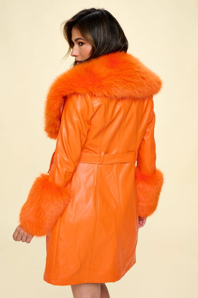 Model wearing orange faux fur trench coat with oversized orange faux fur shawl collar and wide cuffs. Seen from the back 