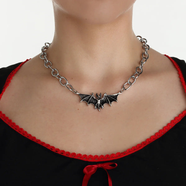 Silver metal oversized link chain toggle necklace with bat pendant. Shown worn by a model in close up