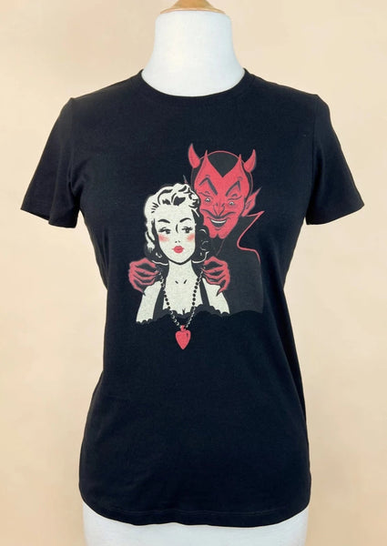 a fitted black cotton t shirt with a retro illustration of a devil putting a heart shaped necklace around the neck of a pinup style woman with blonde hair. Shown on a dress form