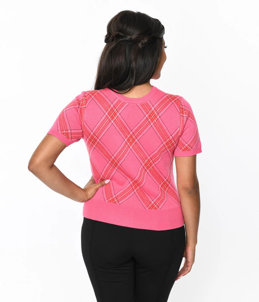 A model wearing a crew neck pullover sweater with short sleeves in a pink, red, and white bias plaid pattern. It has a wide ribbed waistband. Shown from the back untucked 