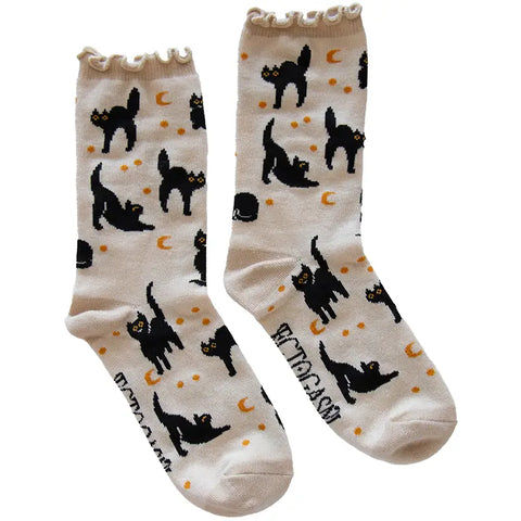Pair of off-white crew socks with ruffle cuff and all-over pattern of black cats with gold crescent moons and stars. Ectogasm logo on bottom of sock. Shown flat