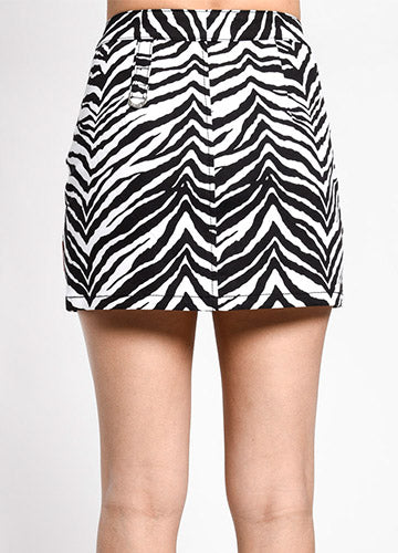Zebra print cotton stretch mini skirt with double snap waistband and zipper down the front with d-ring detail at the left hip. Shown from the back