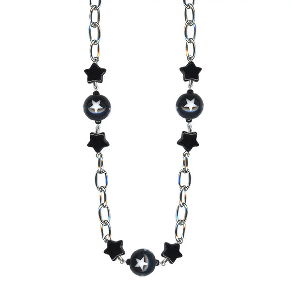 Choker necklace made of silver plated link chain with alternating black star charms and black ball charms decorated with white stars. Shown in close up