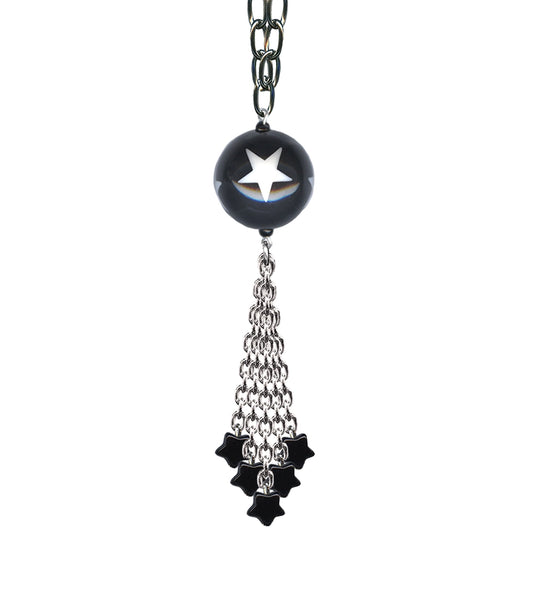 A long silver plated link style chain necklace with a toggle closure and alternating black star charms & black ball charms decorated with white stars. End of the necklace has a tassel made of matching chain with black star charms. Tassel shown in close up