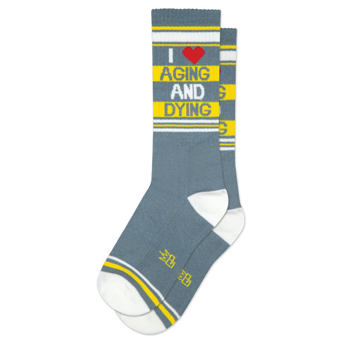 Grey, yellow, and white striped unisex crew socks with a message of “I (heart) AGING AND DYING”