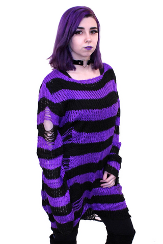 Model wearing an open knit oversized sweater with black and purple stripes and distressed detail at the sleeve and body. Shown from the front