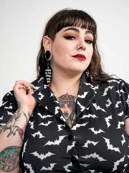 black with allover white bats print short sleeve collared Rosie Dress three button closure bodice, above the knee length a-line silhouette, showing bust close up on model