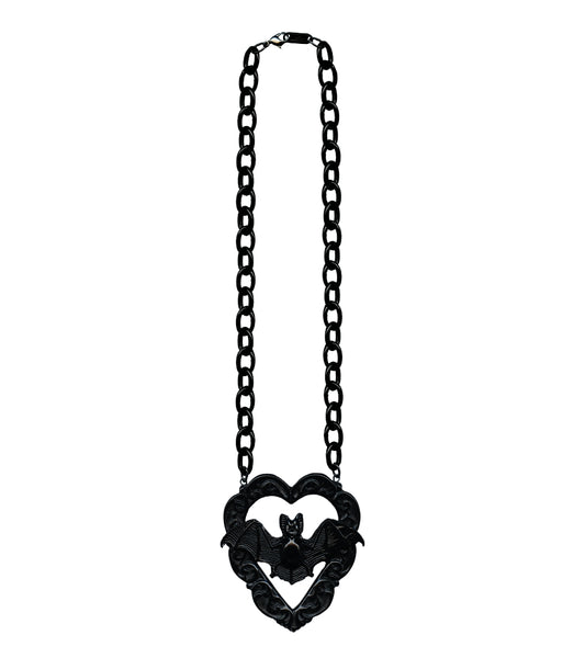 10” necklace with charm of poly resin Victorian style bat in front of ornate carved heart shaped frame. Chain of necklace is oversized black enameled metal chain 