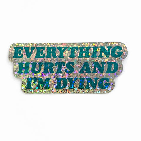 Die-cut holographic sparkly vinyl sticker with message “EVERYTHING HURTS AND I’M DYING” written in dark semi-transparent teal lettering