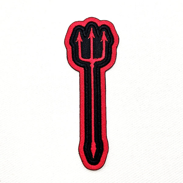 Black and red embroidered patch of a red devil’s pitchfork on a black background with red border. Shown flat