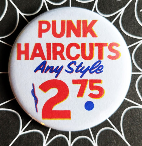 1.25” round pinback button “PUNK HAIRCUTS ANY STYLE $2.75” in red, yellow, and blue old fashioned sign font on white background 