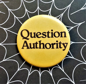 1.25” round pinback button with caption “Question Authority” in black on yellow background 