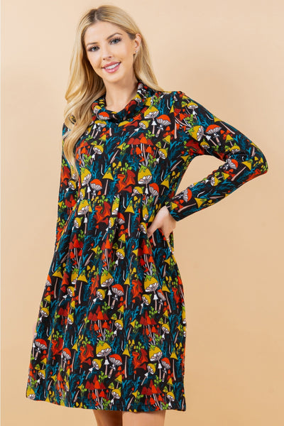 black and multicolored mushroom and forest flora print on a long sleeve fit & flare sweater dress with a cowl neck. Seen on a model in 3/4 shot