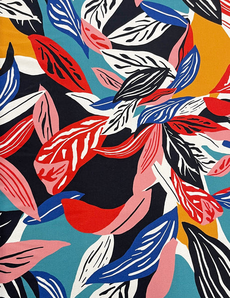 a bright blue, orange, pink, red, white, and black abstract tropical leaf pattern. Design of dress shown in close up