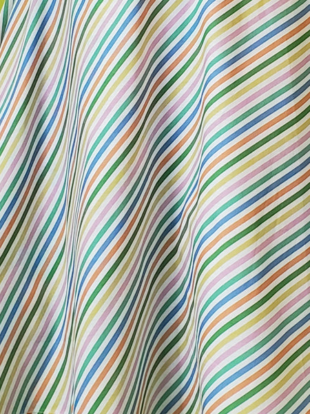 A cotton skater style mini skirt with a wide waistband and a diagonal rainbow stripe pattern on a white background. Showing close up of print