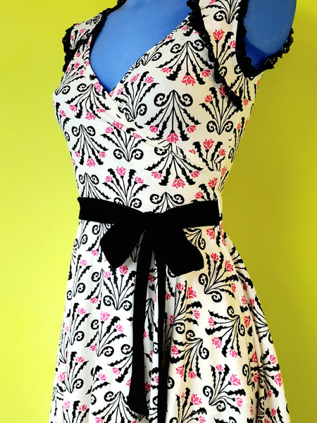 stretch cotton knit sleeveless fit & flare dress in a cream background black & pink damask style floral pattern , showing a cropped close up on a mannequin