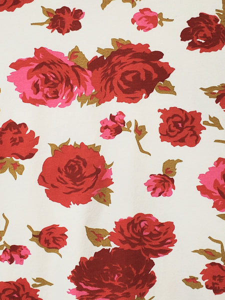 creamy white background blooming pink, red, and green rose pattern fabric close up