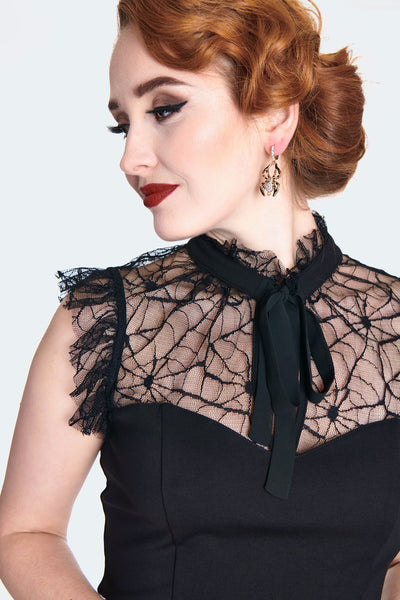 A model wearing a black sleeveless spider patterned lace top with a solid black knit bodice. It has a high frilly lace neck and matching black tie at the collar with a keyhole detail. Shown from front in close up