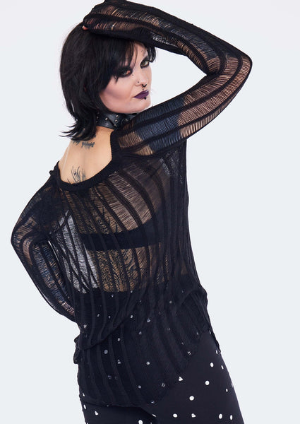 A model wearing a black ladder knit style tunic length sweater with a round neck and oversized long sleeves. Shown from the back