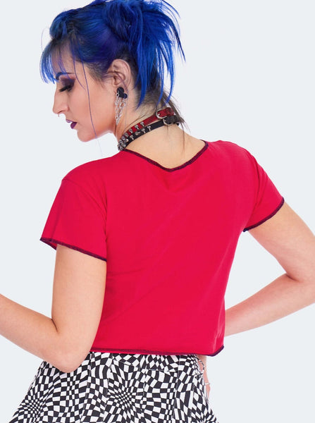 Model wearing a cropped red t-shirt with a black screen printed image of a skeleton’s ribs on the front. Shirt has raw edge with black thread serged edges. Seen from back