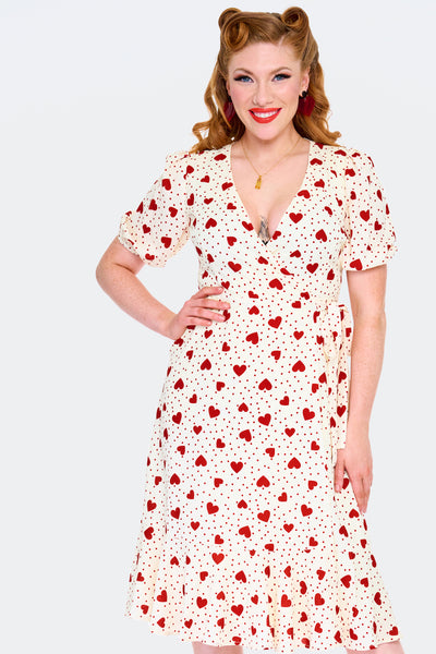 retro style short sleeve knee length wrap dress in red hearts & polka dots print on a cream background print. shown worn by a model.