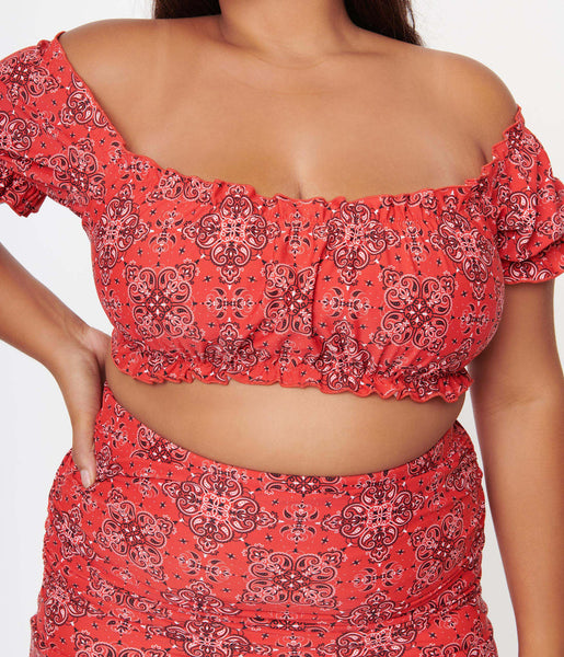 A close up of a swim top in cropped off the shoulder style. It is in a red western bandana print 