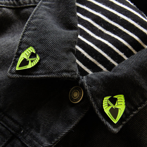 Halloween novelty "Vampire Teeth" in green glow-in-the-dark enamel on black metal clutch-back pin set, shown on denim jacket collar