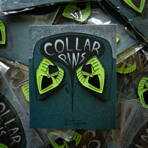 Halloween novelty "Vampire Teeth" in green glow-in-the-dark enamel on black metal clutch-back pin set, shown on illustrated backer card packaging