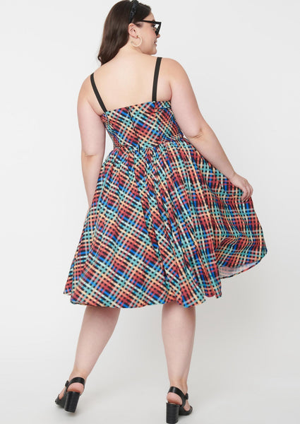 rainbow madras plaid 50s style fit & flare silhouette sundress featuring a princess-seamed bodice with ruched bust sweetheart neckline, applied big black bow and elasticized smocked back panels, removable adjustable straps, and a full swing skirt with side seam pockets in a below the knee length, shown back view on model