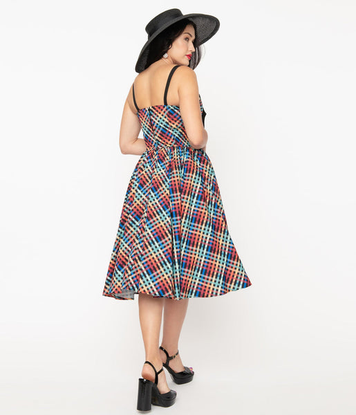 rainbow madras plaid 50s style fit & flare silhouette sundress featuring a princess-seamed bodice with ruched bust sweetheart neckline, applied big black bow and elasticized smocked back panels, removable adjustable straps, and a full swing skirt with side seam pockets in a below the knee length, shown back view on model