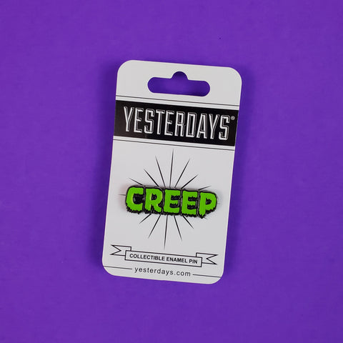 "CREEP" text glow-in-the-dark green and black enameled gunmetal finish metal lapel pin, shown on illustrated cardstock backer packaging