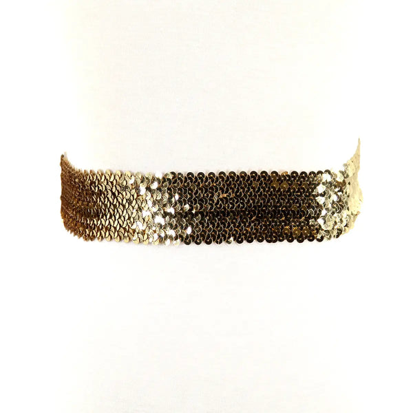 A sparkly gold sequin waist belt with a three pronged silver metal closure in the middle. Seen from behind 