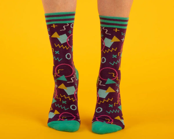 Unisex crew socks in a geometric 80s pattern on a purple background. Shown on a model from the front 