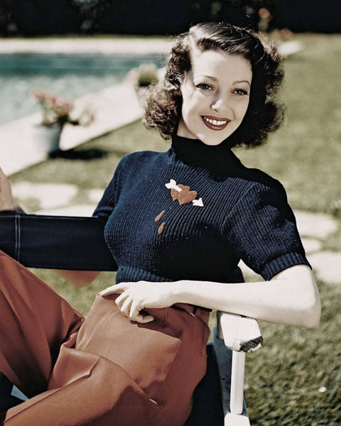 color photgraph of Loretta Young wearing black short sleeve sweater with bleeding hearts pierced by an arrow embroidery