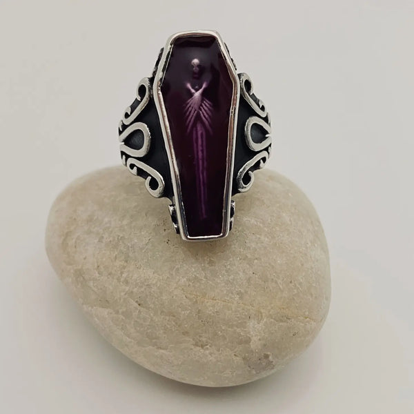 stainless steel ring depicting a vampire encased in translucent purple acrylic resin, at rest in his coffin